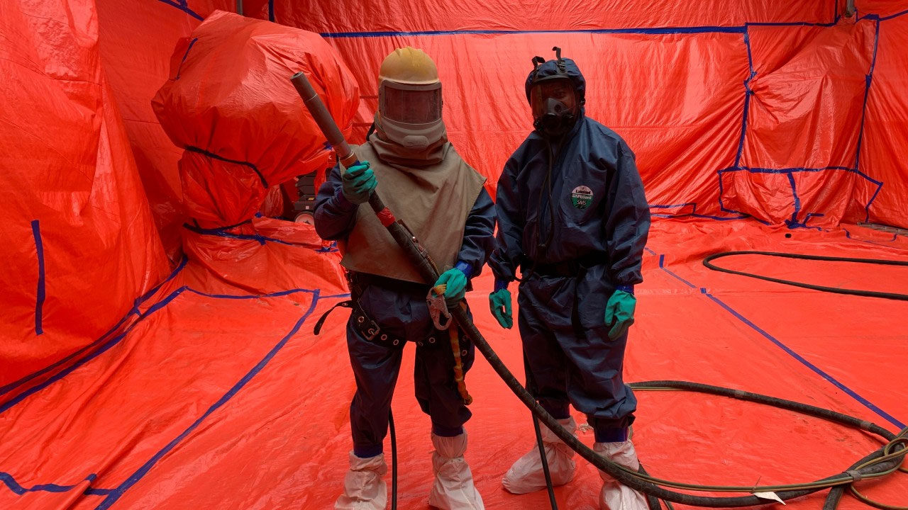 Two professional paint workers prepare a room with red tarp.